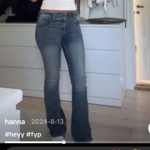 Blå bootcut jeans med låg midja - Säljer ett par klassiska blå bootcut jeans med snygg tvätt och låg midja. Jeansen har fyra fickor, dragkedja och knapp framtill. Perfekta för dig som gillar en retro vibe och vill ha ett par jeans som sitter snyggt över höfterna och släpper ut vid benen.