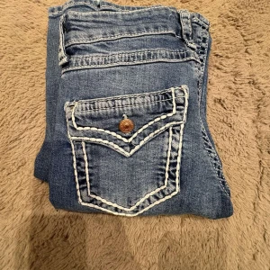 Blå jeans från Gina Tricot young - Snygga blå jeans från Gina Tricot i storlek 158. Klassisk femficksmodell med coola kontrastsömmar och dekorativ bakficka med knapp. Jeansen har normal passform och är tillverkade i mjukt denimtyg. Lite slitage men som inte syns när man har på sig dem