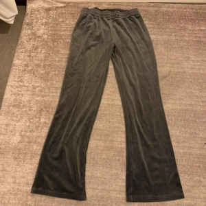 Mörkgrå mjukisbyxor i sammet - Mysiga mörkgrå mjukisbyxor i sammetsmaterial med bootcut-ben och resår i midjan. Perfekta för chill dagar och har en snygg, lite glansig finish. Byxorna har öglor för eventuell snörning i midjan.