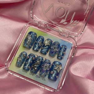 G4ZE (M);Medium Square - Set med blå glittriga gelé lösnaglar i storlek M: 16 mm, 12 mm, 12,5 mm, 11,5 mm, 10 mm. Naglarna har coola 3D-dekorationer i form av silverstjärnor, pärlor och snöflingor. Formen är rundad och designen är riktigt iögonfallande med metallic och holografiska detaljer. Perfekt för dig som vill sticka ut med din nagelstil.