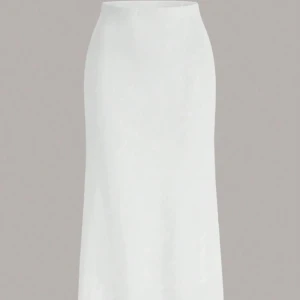 Vit långkjol i satin - Stilren vit långkjol i satin med slät yta och elegant fall. Kjolen har en klassisk rak passform som sitter snyggt i midjan och ger en clean look. Perfekt för dig som gillar minimalistisk stil och vill ha något enkelt men ändå classy.