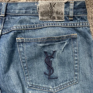 Ysl jeans - Blå straight fit jeans från Yves Saint Laurent med klassisk straight fit och normal passform. Snyggt YSL-broderi på bakfickan. Jeansen är i storlek w36 l36 men sitter mer som 34/36. Hör av er om ni har frågor.