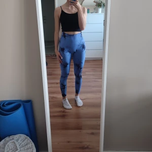 Blå tie-dye leggings med hög midja - Säljer ett par blå leggings med svart tie-dye mönster. De är högmidjade och sitter tight, perfekta för träning eller chill. Materialet är stretchigt och mjukt syntet, vilket gör dem riktigt bekväma. Snygg passform som framhäver benen och midjan. Finns även i ljusblå. 100 kr för en eller 160 kr för båda.