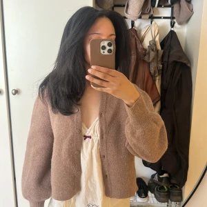 Brun kofta från Stockh LM i ullmix - Mysig brun kofta från Stockh LM i ullmix med v-ringning, krage och knappar framtill. Koftan har ballongärmar och ribbade muddar som ger en chill och trendig look. Lite nopprig fråga efter fler bilder❤️