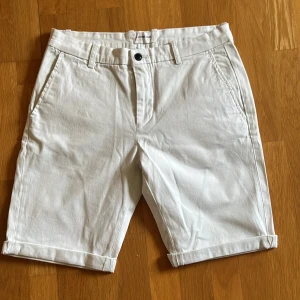 Vita shorts från Lindbergh - Vita shorts från Lindbergh med klassisk design. De har en knapp och dragkedja framtill samt fickor både fram och bak.
