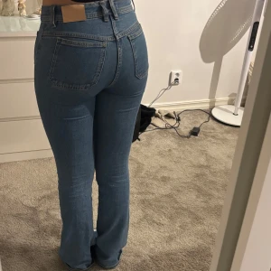 Blå bootcut jeans - Snygga blå bootcut jeans med hög midja. Klassisk design med fem fickor och knappgylf. Perfekta för en avslappnad stil.
