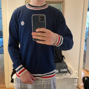 Mörkblå tröja från Moncler - Säljer en snygg mörkblå tröja från Moncler med vita och röda ränder vid hals. Tröjan är inte riktigt xl eftersom jag kan använda den som är medium.