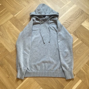 Grå merinoull hoodie - Säljer en sprillans ny merinoull hodie med långa ärmar och justerbar huva. Perfekt för en avslappnad look. Den har ribbade muddar vid ärmslut och nederkant för extra komfort. Hör av er vid funderingar och frågor!