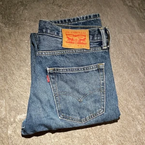 Levi's 502 jeans i blå denim - Levi’s 502 jeans – stl 32/34  Säljer ett par Levi’s 502 jeans i storlek 32/34. Modellen har en modern, något avsmalnande passform som är både bekväm och stilren. Perfekta för vardagsbruk och enkla att matcha.  ✔ Märke: Levi’s ✔ Modell: 502 (Regular Taper Fit) ✔ Storlek: 32/34 ✔ Färg: Mörkblå denim  ✔ Skick: Bra – endast en liten slitning vid bakfickan  Finns för avhämtning eller kan skickas! Skicka PM vid intresse.