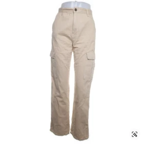 Beige cargopants från STR - Säljer ett par beige cargopants från STR. Byxorna har flera fickor och en knappstängning i midjan.  Använda en gång.