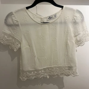 Vit blus med spetsdetaljer💗 - Säljer en söt, vit och blommig sommartopp från Holister💗 använd fåtal gånger men den är ändå fräsch💗
