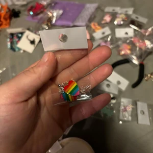 Regnbågsfärgat hjärtformat örhänge - Säljer ett färgglatt örhänge i form av ett hjärta med regnbågsfärger. Perfekt för att lägga till en pop av färg till din outfit. Örhänget är förpackat i en plastpåse.