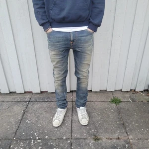 Nudie jeans  - Snygga blå jeans från nudie med en klassisk tvätt och normal passform. Byxorna har en midwaist-design och är perfekta för en avslappnad stil. De har en dragkedja och knappar framtill. Strl w30 L32