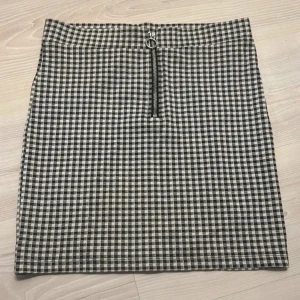 Rutig kjol med dragkedja - Snygg rutig kjol i svart och vit med en dragkedja framtill. Perfekt för en stilren look. Kjolen har en kort längd och passar bra till olika tillfällen.