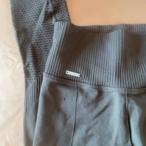 Seamless tights från Aim'n - Leggings från Aim'n med hög midja och ribbad detalj vid midjan. De har ett diskret mönster längs benen som är hål. Perfekta för träning eller en avslappnad dag. Finns en liten knott. 