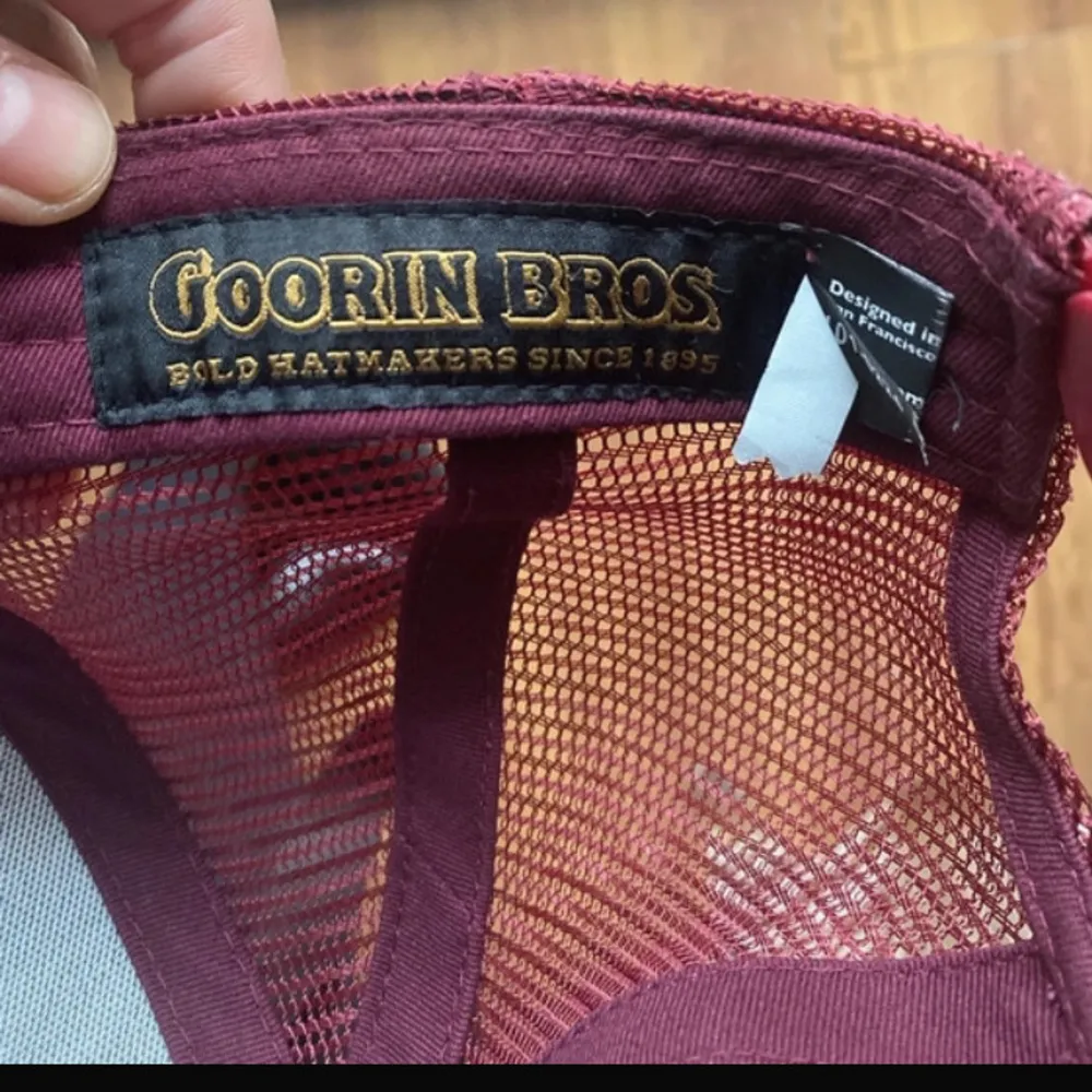 Snygg vinröd keps från Goorin Bros med ett broderat rävmotiv och texten 'FOXY' på framsidan. Kepsen har ett nätmaterial på baksidan och justerbar passform.. Asusteet.