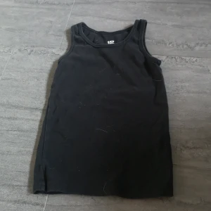 Svart linnetopp från 157 - Säljer en svart linnetopp från 157 i 100% ekologisk bomull. Perfekt för varma dagar eller som ett basplagg i garderoben. Enkel och stilren design.