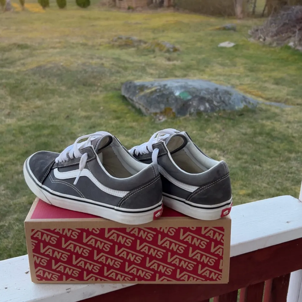 Säljer ett par klassiska gråa Vans sneakers med vit sula och vit sidostrimma. Skorna har snörning och är perfekta för en avslappnad stil. De kommer i originalkartong.. Kengät.
