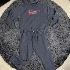 Grå tracksuit från Nike - Säljer en grå tracksuit från Nike med röd logga i storlek XL. Perfekt för en avslappnad och oversized stil. Säljes då den bara ligger i min garderob utan att komma till användning då det inte är min stil längre. Pris kan diskuteras.