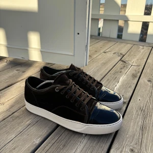 Lanvins uk 10 passar 44/45 - Snygga bruna sneakers med en unik kombination av mocka och lackdetaljer på tån. Skorna har en vit sula och klassisk snörning. Perfekta för dig som vill ha en stilren men ändå iögonfallande look. Bra skicka inga större defekter inget og tillkommer kvitto finns ej, priset går att diskutera vid snabb affär.