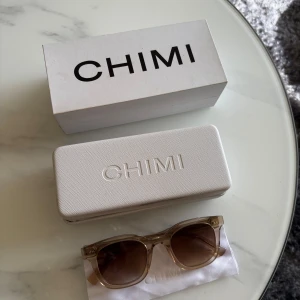 Solglasögon från CHIMI - Snygga solglasögon från CHIMI med transparenta bågar och bruna linser. Perfekta för en stilren look. Kommer med originalförpackning och fodral.