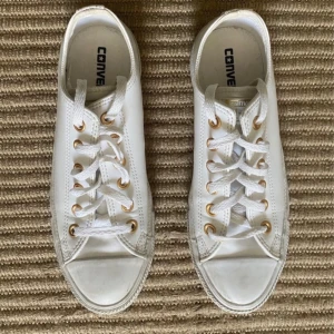 Vita Converse sneakers i skinn - Snygga vita Converse sneakers i skinn med klassisk låg modell. Skorna har vita snören, guldfärgade öljetter och en platt sula. Passar till allt och är superenkla att matcha.