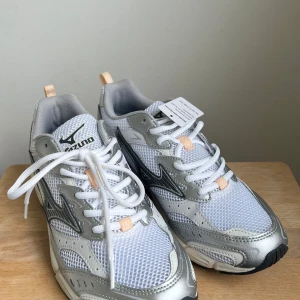 Vita/silver Mizuno sneakers - Superfräscha, helt nya sportstyle-skor från Mizuno i vitt och silver med detaljer i peach. Köpte fel storlek så de säljs helt oanvända och i originalkartong. 