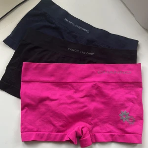 3-pack oanvända shorts/underbyxor Panos Emporio & Channo - Tre par sömlösa shorts/underbyxor i olika färger: ett par marinblå och ett par svarta från Panos Emporio samt ett par knallrosa från Channo med en liten blomdetalj. Alla har bred resår i midjan och är tillverkade i stretchigt nylon material, perfekta för träning eller chill. Storlek XS 🖤💙💗Alla för 60kr.