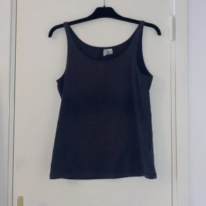 Mörkgrå linnetopp i bomull - En basic mörkgrå linnetopp med smala axelband. Toppen är tillverkad i mjuk bomull och har en enkel, rak passform. Perfekt att styla med jeans eller shorts för en clean look. OBS nopprig (hela varan)  