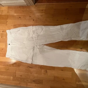 Vita byxor från Grunt i bomull XL(barnstorlek) - Säljer ett par vita byxor från Grunt i storlek XL(barnstorlek). De har elastisk midja och är gjorda i mjuk bomull, perfekta för en chill och avslappnad stil. Byxorna har raka ben och enkel design utan synliga detaljer.