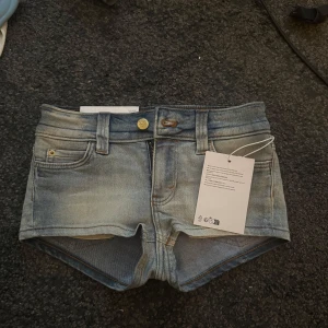 Cheap Monday ljusblå jeansshorts - Snygga ljusblå jeansshorts från Cheap Monday med låg midja och slitna detaljer. Shortsen har bälteshällor, knapp och dragkedja framtill samt en cool tvättad look. Perfekta till sommaren och festivaler. Köpt från Weekday för 300kr men märket är Cheap Monday. Säljer på grund av att jag köpte fel storlek❤️