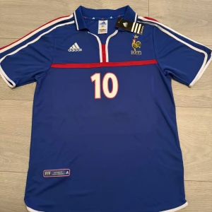 Frankrike Zidane 10 Adidas fotbollströja - Klassisk blå Frankrike fotbollströja från Adidas med nummer 10 och Zidane på ryggen. Storlek M