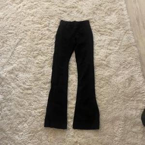 Svarta kostymliknande bootcut byxor - Säljer ett par svarta bootcut kostymliknande byxor med hög midja. De har en snygg utsvängd passform och är perfekta för dig som gillar en stilren look❣️                                    OBS! Lappen är bort klippt!