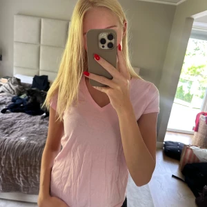 Rosa T-shirt med V ringning från Ralph Lauren - Snygg, stilren rosa T-shirt från Ralph Lauren i Stolek S. Perfekt som ett bas plagg eller att bara ha som den är. Perfekt passform