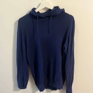 Mörkblå hoodie från Ombre - Säljer en stilren mörkblå hoodie från Ombre i storlek M. Tröjan har huva med snörning och långa ärmar. Perfekt för dig som gillar en enkel och klassisk look. Materialet känns mjukt och bekvämt mot huden.