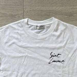 Vit Saint Laurent t-shirt med tryck - Ny och Oanvänd vit t-shirt från Saint Laurent med logotyp-tryck både fram och bak. Perfekt för dig som vill ha en snygg look! Kom med frågor!😁