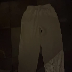 Beiga linnebyxor från RYVLS med snörning - Snygga och luftiga beiga linnebyxor från RYVLS. Byxorna har elastisk midja med snörning och två sidofickor. Perfekta för varma dagar när du vill ha en chill och avslappnad stil.