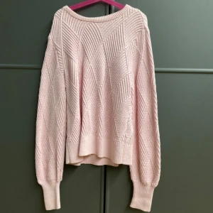 Ljusrosa stickad tröja från ONLY - Superfin ljusrosa stickad tröja från ONLY med snyggt strukturmönster i diagonala ränder. Tröjan har rund halsringning, långa ärmar och breda muddar vid ärmslut och nederkant. Perfekt för lager på lager under kyliga dagar. Aldrig använd!