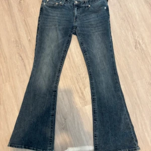 Blå bootcut jeans från True Religion - Snygga blå bootcut jeans från True Religion med rosa detaljer. Fråga gärna om ni undrar något!! Använt en gång och original priset var 140€, har kvar lappen som kom med (där står tyvärr inget pris dock)