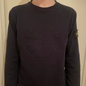 Mörkblå tröja från Stone Island - Säljer en mörkblå tröja från Stone Island i storlek small med deras ikoniska logga på ärmen. Tröjan har ett fint skick och en ovanlig logga på magen. Pris kan diskuteras.