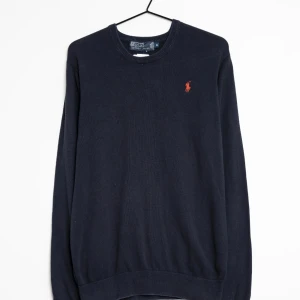 Mörkblå tröja från Ralph Lauren - Snygg mörkblå tröja från Ralph Lauren med det klassiska logotypbroderiet i rött på bröstet. Tröjan har rund hals och långa ärmar, perfekt för en stilren look.