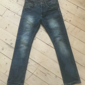 Blå jeans från Diesel - Säljer ett par snygga blå jeans från Diesel med en klassisk femficksdesign och en cool tvättad look. De har en knappgylf och en läderpatch med Diesel-loggan på baksidan. Perfekta för en avslappnad stil.