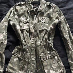 Camouflagejacka från ONLY - Tunnare jacka med camoflagemönster och nitar, 1 nit på ena fickan har lossnat, storlek s, normal i storleken och går justera i midjan, 