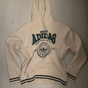 Beige hoodie från Adidas - Säljer en snygg beige hoodie från Adidas med tryck i grönt och svart 💕
