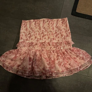 Rosa blommig kjol med volang - Söt rosa kjol med blommigt mönster och volangdetalj, skulle säga att den passar s-l