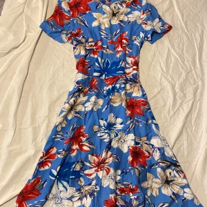 Blommig klänning i blått och rött - Aldrig använt i perfekt skick. Perfekt för somriga dagar! 
