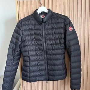 Svart dunjacka från Colmar - Snygg svart dunjacka från Colmar med dragkedja framtill och en stilren design. Jackan har långa ärmar och en liten logotyp på ärmen. Perfekt för kyligare dagar.