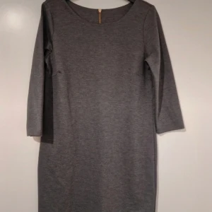 Grå klänning med dragkedja - Snygg grå klänning med trekvartsärm och en stilren dragkedja i ryggen. Perfekt för en chic och enkel look.