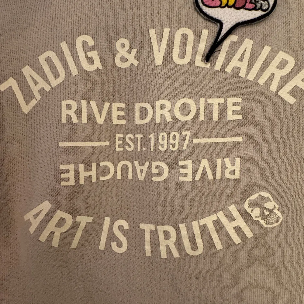Säljer en beige tröja från Zadig & Voltaire med texten 'Art is Truth' och ett färgglatt märke längst upp. Tröjan har långa ärmar och rund halsringning. Perfekt för en avslappnad stil.. Neuletakit & Villapaidat.