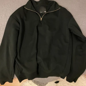 Svart tröja med dragkedja - Säljer en stilren svart tröja från H&M med dragkedja vid halsen. Tröjan har långa ärmar och en bekväm passform, perfekt för kyligare dagar. Passar bra till både jeans och chinos.